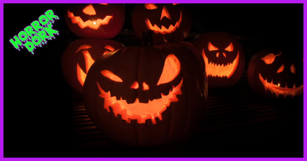 Group of glowing jack-o’-lanterns with sinister carved faces, lit against a dark background.”