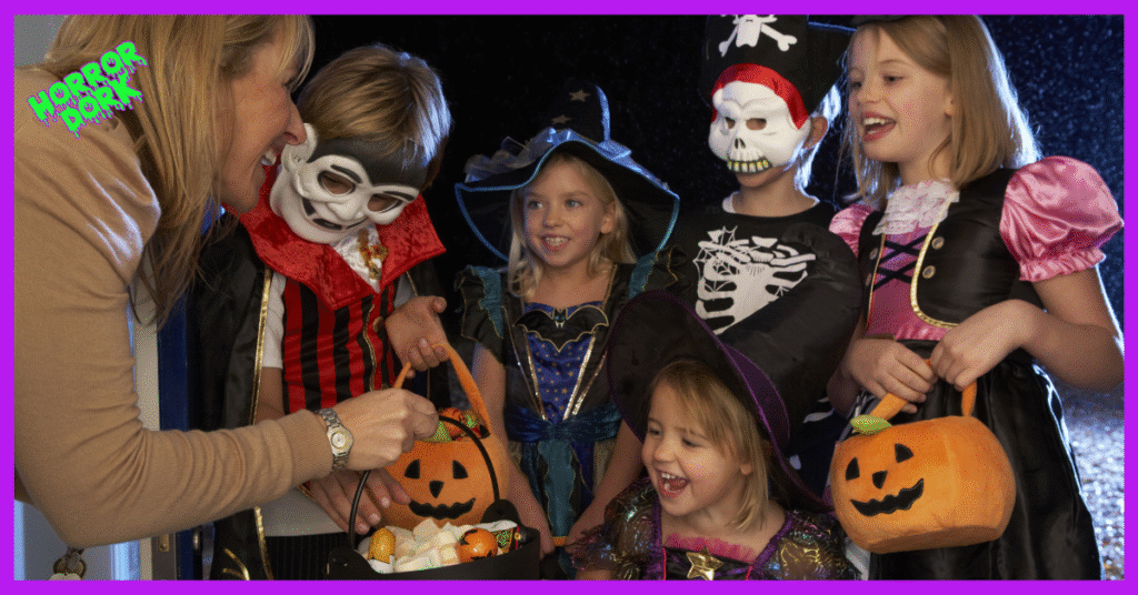 Children in Halloween costumes trick-or-treating at night, holding pumpkin baskets and smiling as candy is handed out.